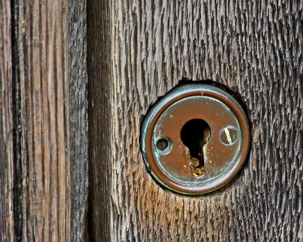 An old keyhole in a weathered wooden door, settling a loved one's estate through probate