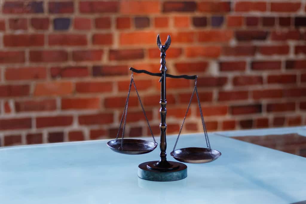 Una balanza sobre una mesa frente a un muro de ladrillo: el peso de la evidencia