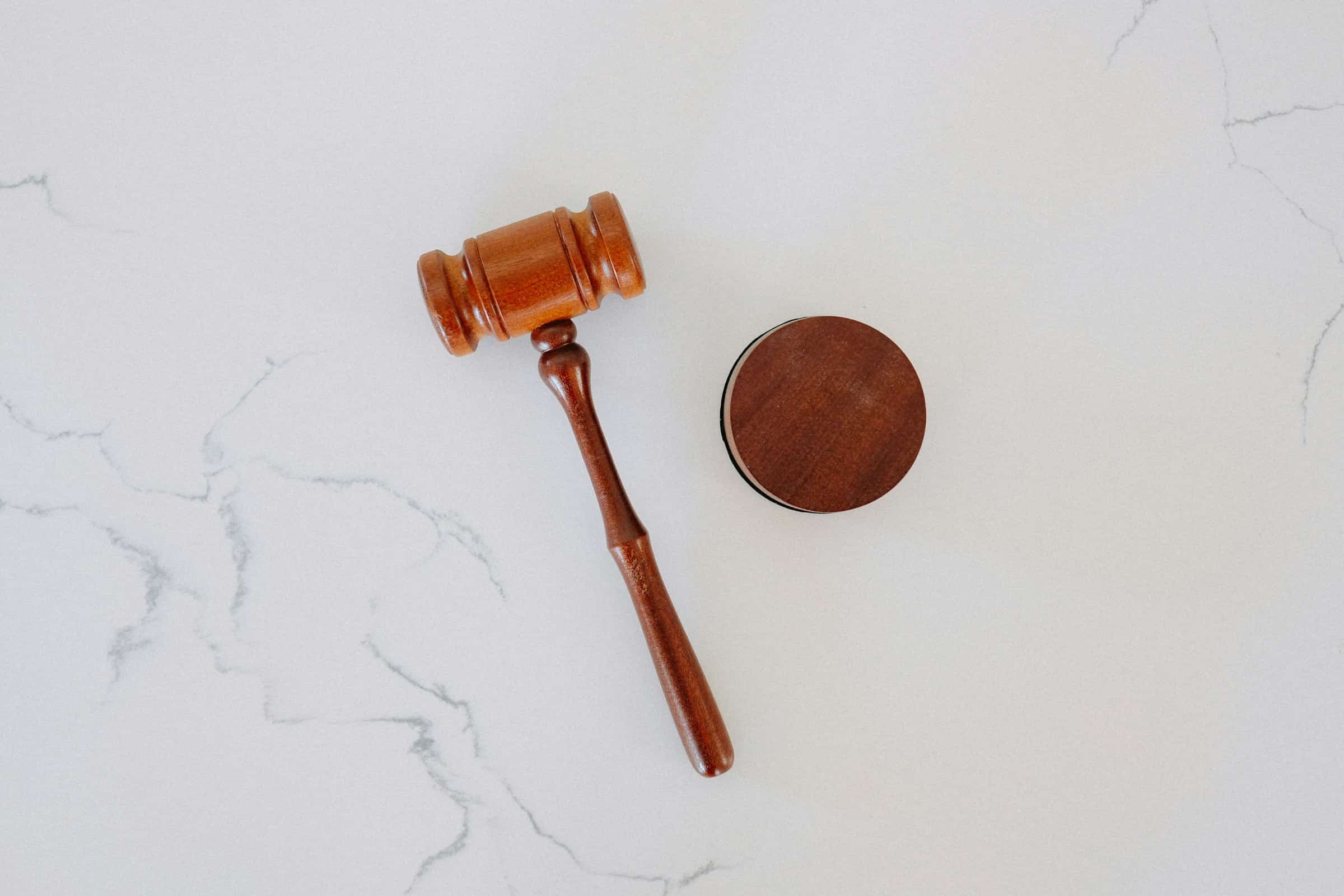 A wooden gavel and sound block resting on a marble surface