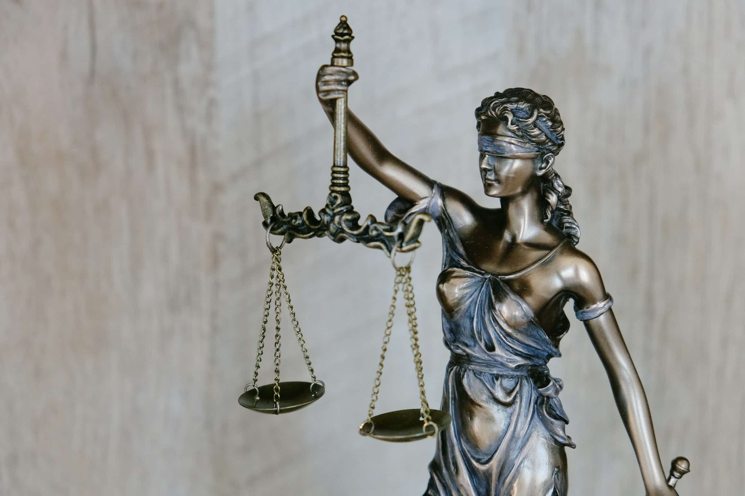 A bronze statue of Lady Justice holding balanced scales